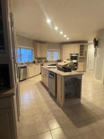 kitchen with light brown cabinetry, sink, stainless steel appliances, and a kitchen island with sink