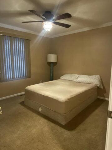 carpeted bedroom featuring ceiling fan and crown molding