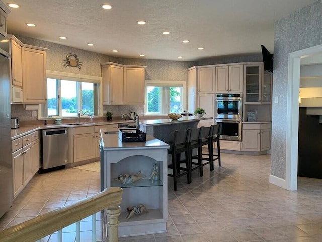 kitchen with stainless steel appliances, sink, a breakfast bar, a center island with sink, and cream cabinetry