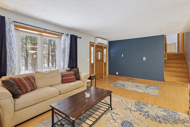 living room featuring a textured ceiling, a wall mounted AC, and light hardwood / wood-style floors