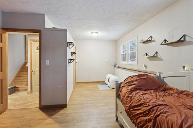 bedroom with a textured ceiling and light hardwood / wood-style flooring