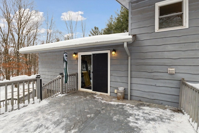 snow covered property entrance with a wooden deck