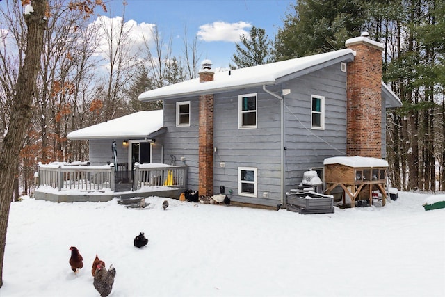 snow covered back of property with a wooden deck