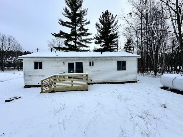 snow covered house featuring a wooden deck