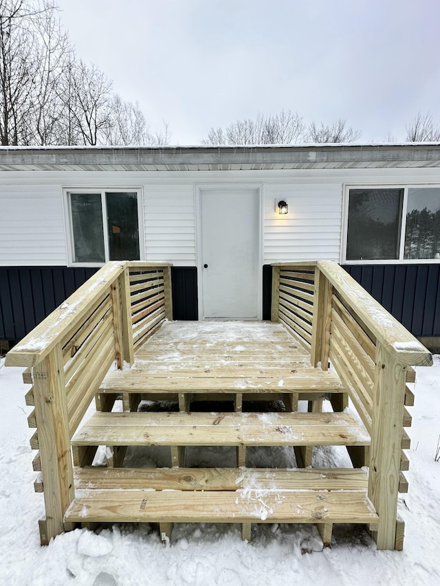 snow covered property entrance featuring a deck