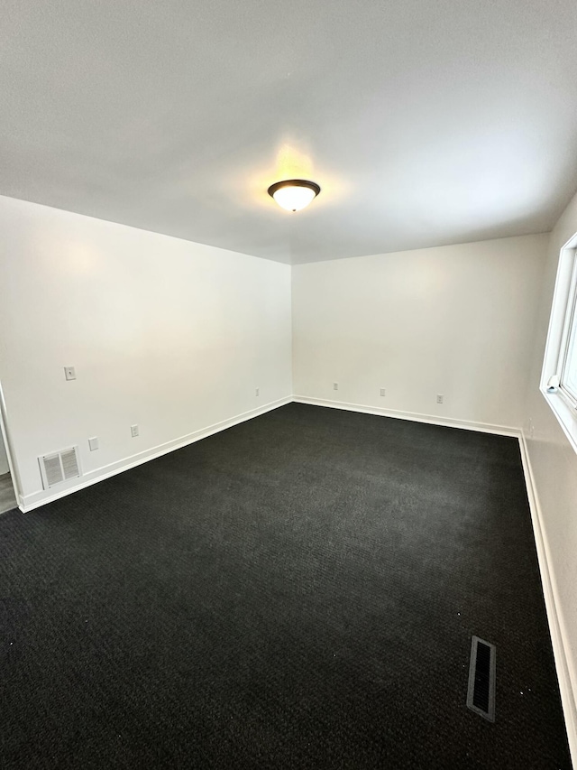 unfurnished room featuring dark carpet