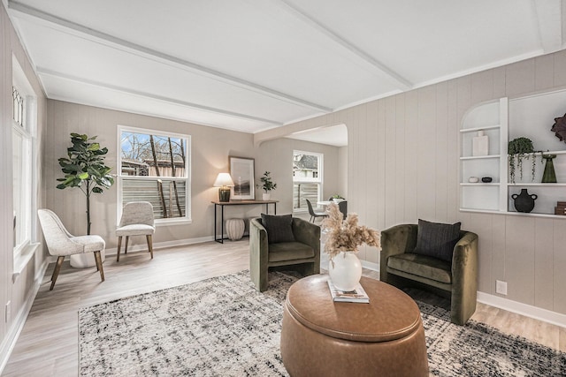 living room with wood walls, plenty of natural light, light hardwood / wood-style flooring, and beamed ceiling