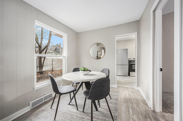 dining room with wood-type flooring and wood walls