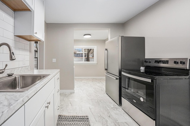 kitchen featuring appliances with stainless steel finishes, white cabinetry, tasteful backsplash, sink, and light stone counters