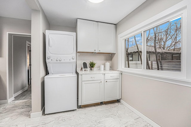 laundry room with stacked washer and clothes dryer and cabinets