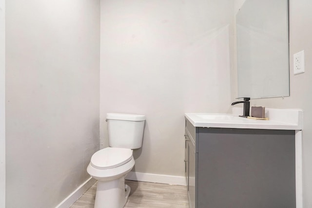 bathroom with toilet, vanity, and hardwood / wood-style flooring