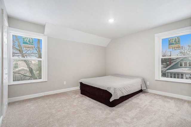 carpeted bedroom with lofted ceiling and multiple windows