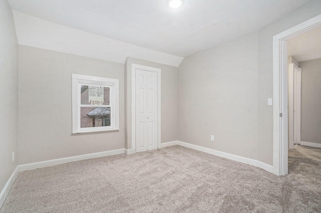 carpeted empty room featuring vaulted ceiling