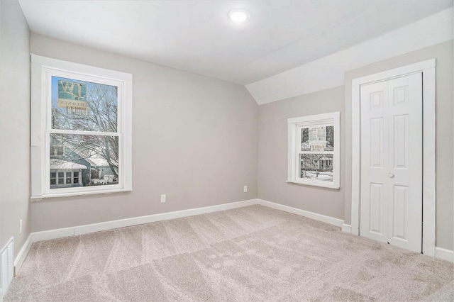 spare room featuring a wealth of natural light, light carpet, and lofted ceiling