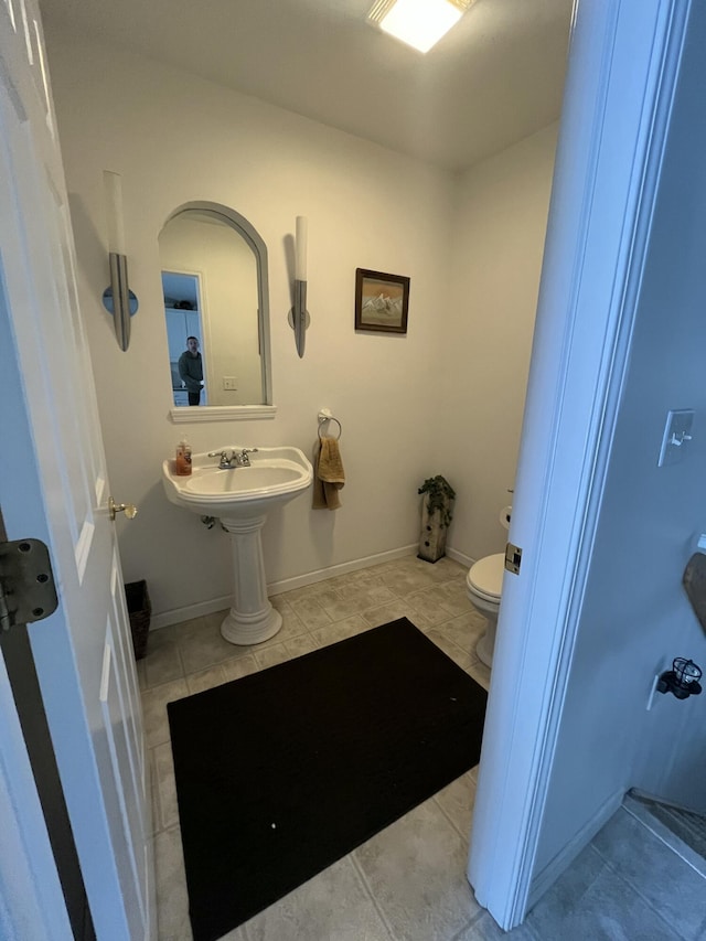 bathroom featuring toilet, tile patterned floors, and sink