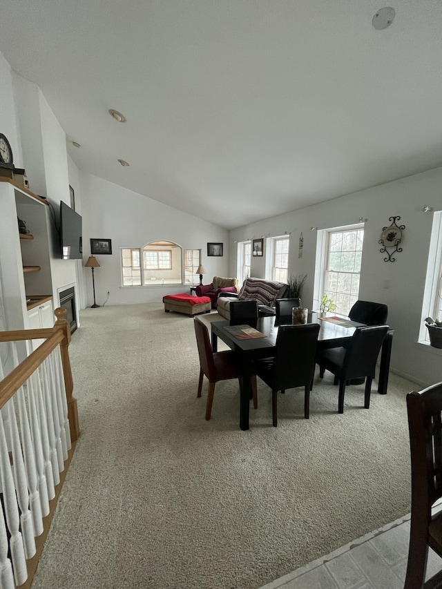 carpeted dining space with lofted ceiling