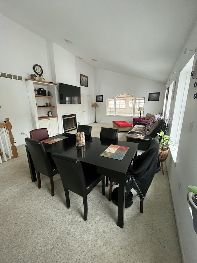 dining area featuring light carpet and vaulted ceiling