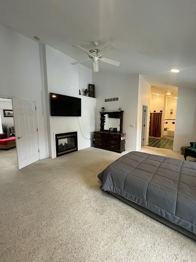 bedroom with ceiling fan, connected bathroom, carpet floors, and vaulted ceiling