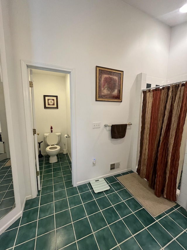 bathroom featuring toilet, tile patterned floors, and walk in shower