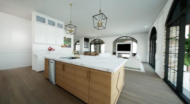 kitchen featuring light stone countertops, a large island with sink, white cabinets, sink, and white dishwasher