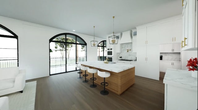 kitchen with tasteful backsplash, white cabinets, light stone counters, and a kitchen island