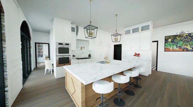 kitchen with a breakfast bar area, a kitchen island, double oven, white cabinets, and sink