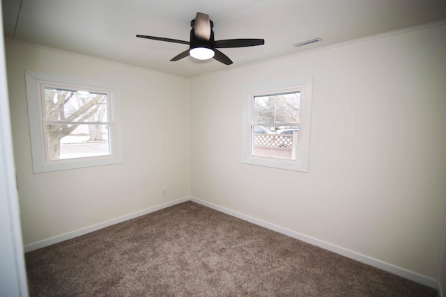 carpeted empty room with ceiling fan, a wealth of natural light, and ornamental molding