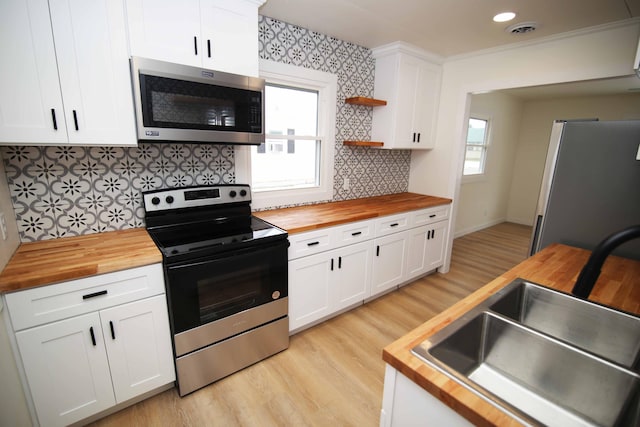 kitchen featuring white cabinetry, butcher block countertops, and appliances with stainless steel finishes