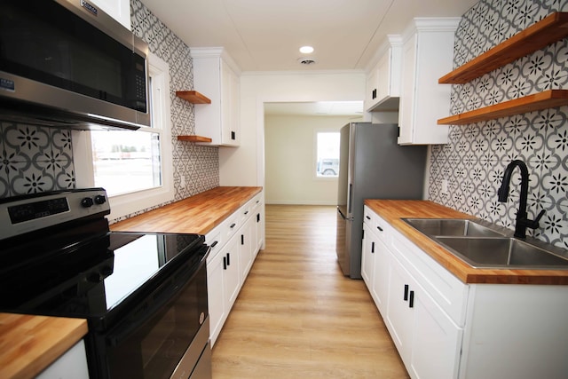 kitchen featuring white cabinets, wooden counters, sink, and stainless steel appliances