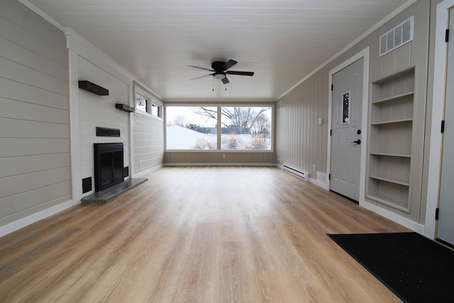 unfurnished living room featuring built in shelves, a baseboard heating unit, light wood-type flooring, ceiling fan, and crown molding