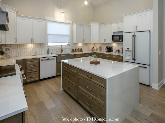 kitchen featuring decorative light fixtures, light stone counters, white appliances, and white cabinets