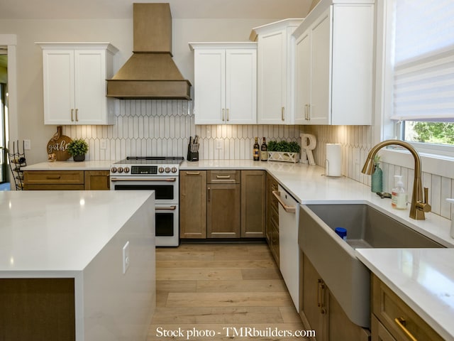 kitchen featuring white cabinets, custom range hood, tasteful backsplash, and white appliances