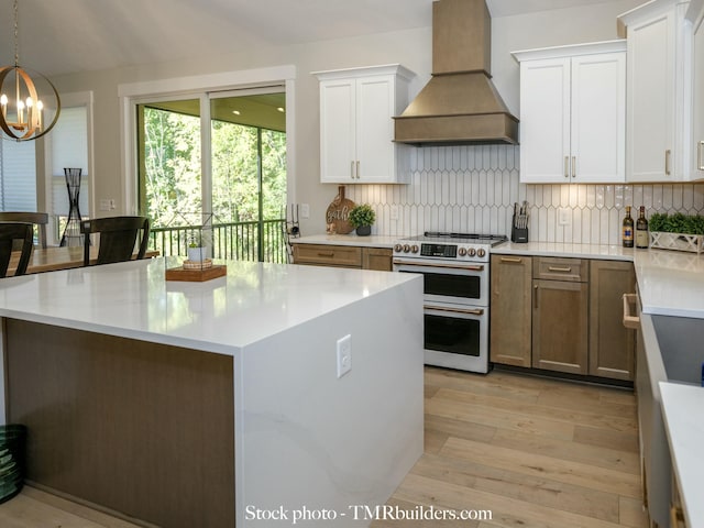 kitchen featuring custom exhaust hood, white cabinetry, decorative backsplash, double oven range, and hanging light fixtures