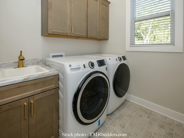 clothes washing area with sink, washer and dryer, and cabinets