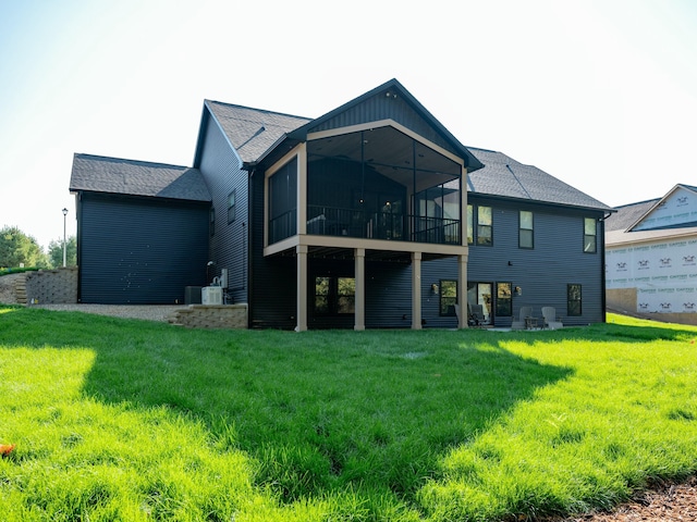 rear view of house with central AC unit, a sunroom, and a lawn