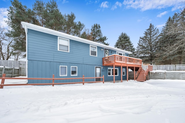 snow covered rear of property with a deck