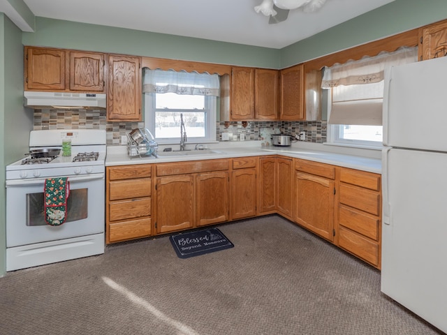 kitchen with sink, a wealth of natural light, white appliances, and dark carpet