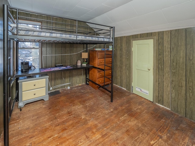 bedroom with hardwood / wood-style flooring and wood walls