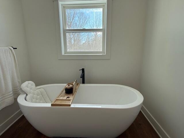 bathroom with a bath and hardwood / wood-style floors