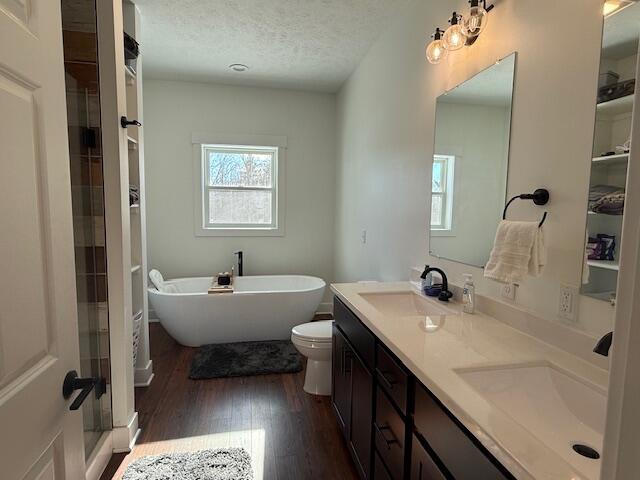 bathroom featuring a textured ceiling, a bathing tub, a healthy amount of sunlight, and wood-type flooring