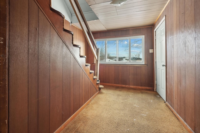 doorway with light carpet and wooden walls