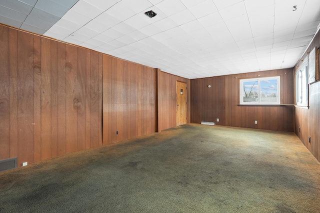 empty room featuring carpet floors and wood walls