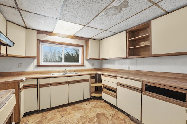 kitchen featuring wood counters, sink, a paneled ceiling, and cream cabinetry