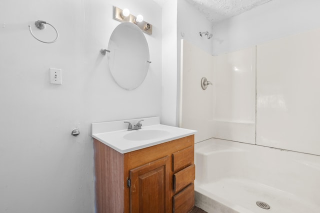 bathroom with vanity, a textured ceiling, and a shower