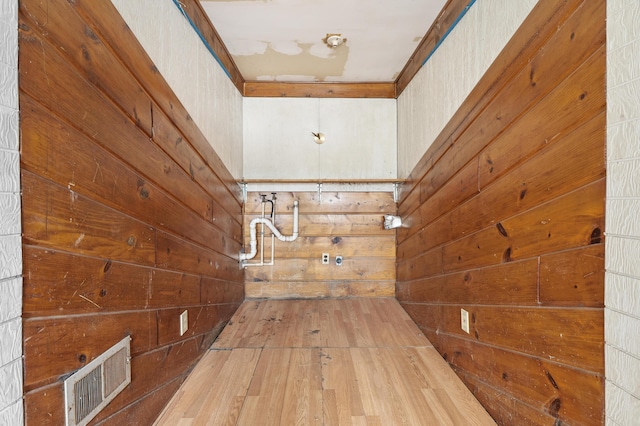 hallway with ornamental molding, wooden walls, and hardwood / wood-style floors