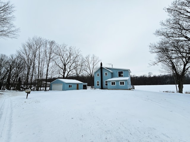 snow covered property featuring an outbuilding and a garage