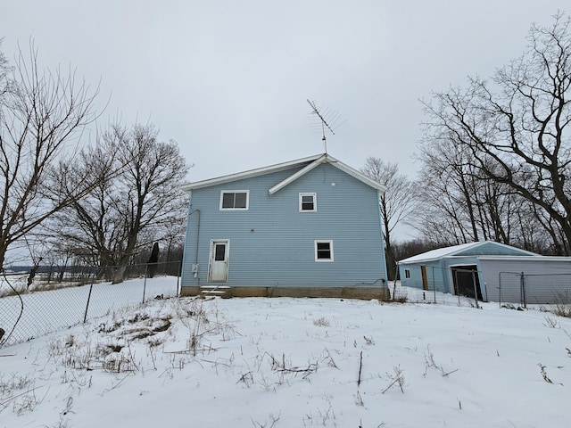 snow covered back of property with a garage