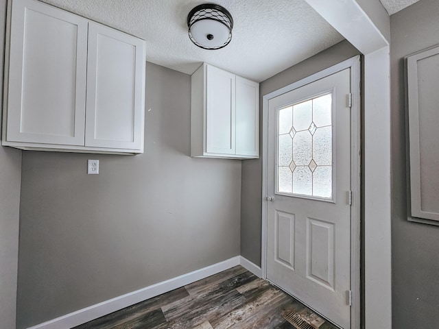 doorway to outside with a textured ceiling and dark hardwood / wood-style flooring