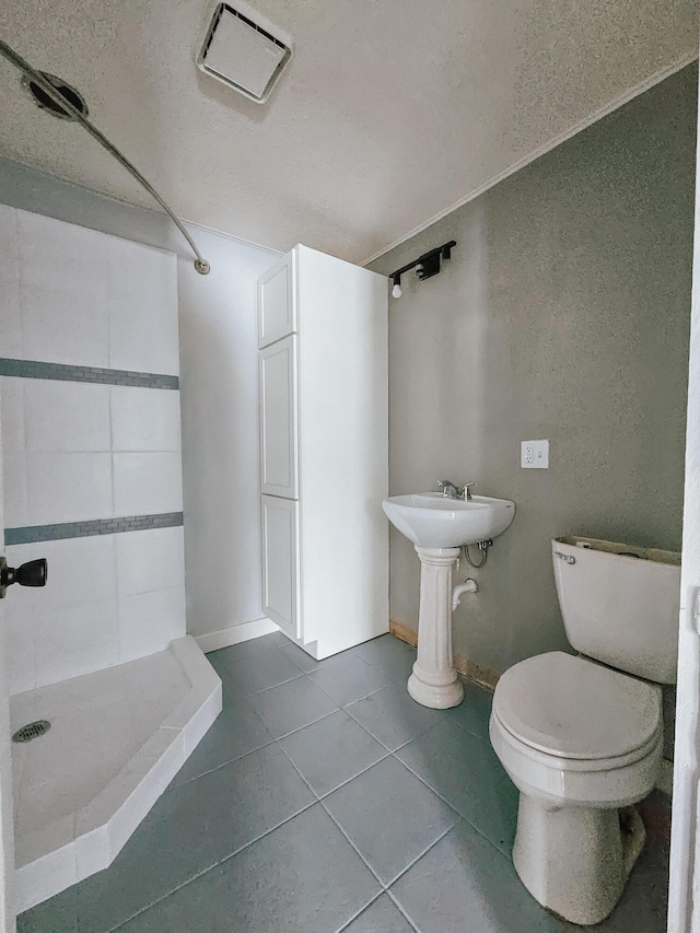 bathroom featuring toilet, a shower, and tile patterned flooring