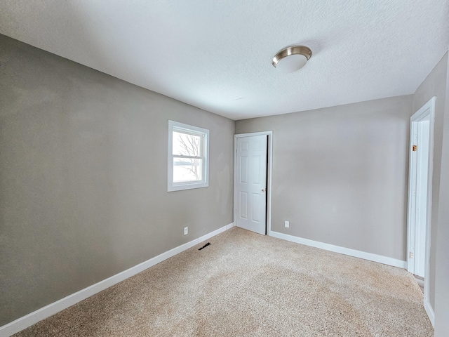 spare room with a textured ceiling and carpet flooring